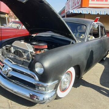 Matowy czarny Ford z 1950 roku z kompresorem – shoebox, który pokazuje silnik