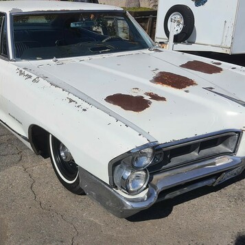 Biały Pontiac z połowy lat 60. w patynie – pionowe reflektory i rdza na masce