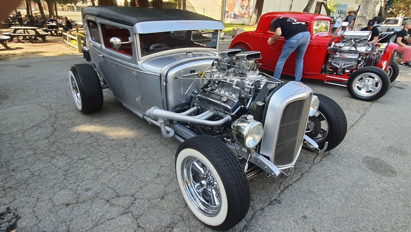 Srebrny Ford Model A Tudor z kompresorem – hot rod z czarnym dachem na białych ściankach