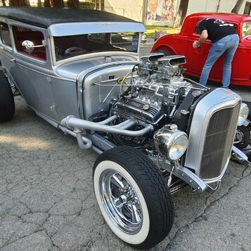 Srebrny Ford Model A Tudor z kompresorem – hot rod z czarnym dachem na białych ściankach