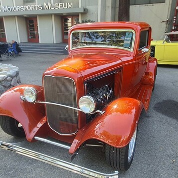 Pomarańczowo-czerwony Ford 3-window coupe z 1932 roku – Deuce w kolorze tangerine przed Muzeum NHRA