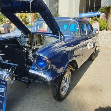 Granatowy Chevrolet z 1957 roku jako gasser – wtrysk Hilborn z chromowanymi lejkami pod otwartą maską