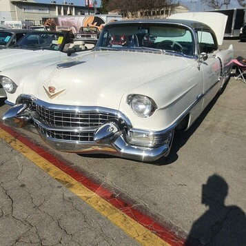 Biały Cadillac z 1955 roku – chromowane „Dagmary” i atrapa egg-crate w kolorze śniegu