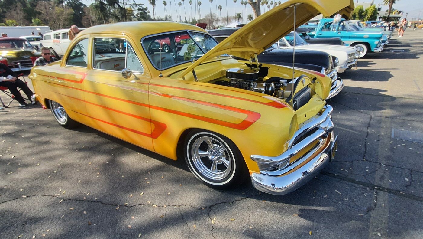 Żółty Ford z 1953 roku z pomarańczowymi pasami – kustom z otwartą maską w kolorach lata