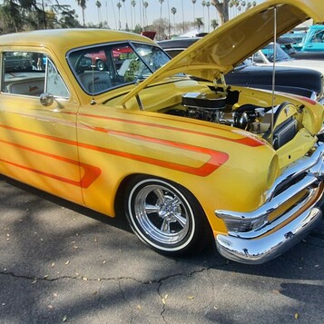 Żółty Ford z 1953 roku z pomarańczowymi pasami – kustom z otwartą maską w kolorach lata