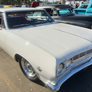 Biały Chevrolet Chevelle Malibu z 1965 roku z czarnym dachem – hardtop na chromowanych kołpakach