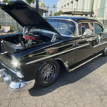 Czarny Chevrolet Bel Air z 1955 roku z otwartą maską – „55 Chevy” na czarnych felgach z obu stron