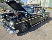 Czarny Chevrolet Bel Air z 1955 roku z otwartą maską – „55 Chevy” na czarnych felgach z obu stron – zdjęcie 1