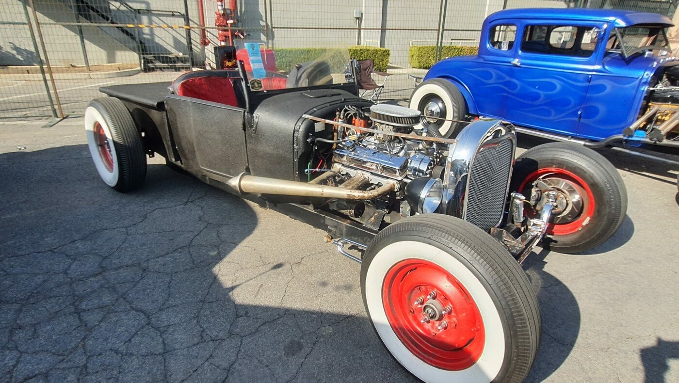 Rat rod pickup na czerwonych felgach z szerokimi białymi ściankami – surowa blacha i silnik na wierzchu