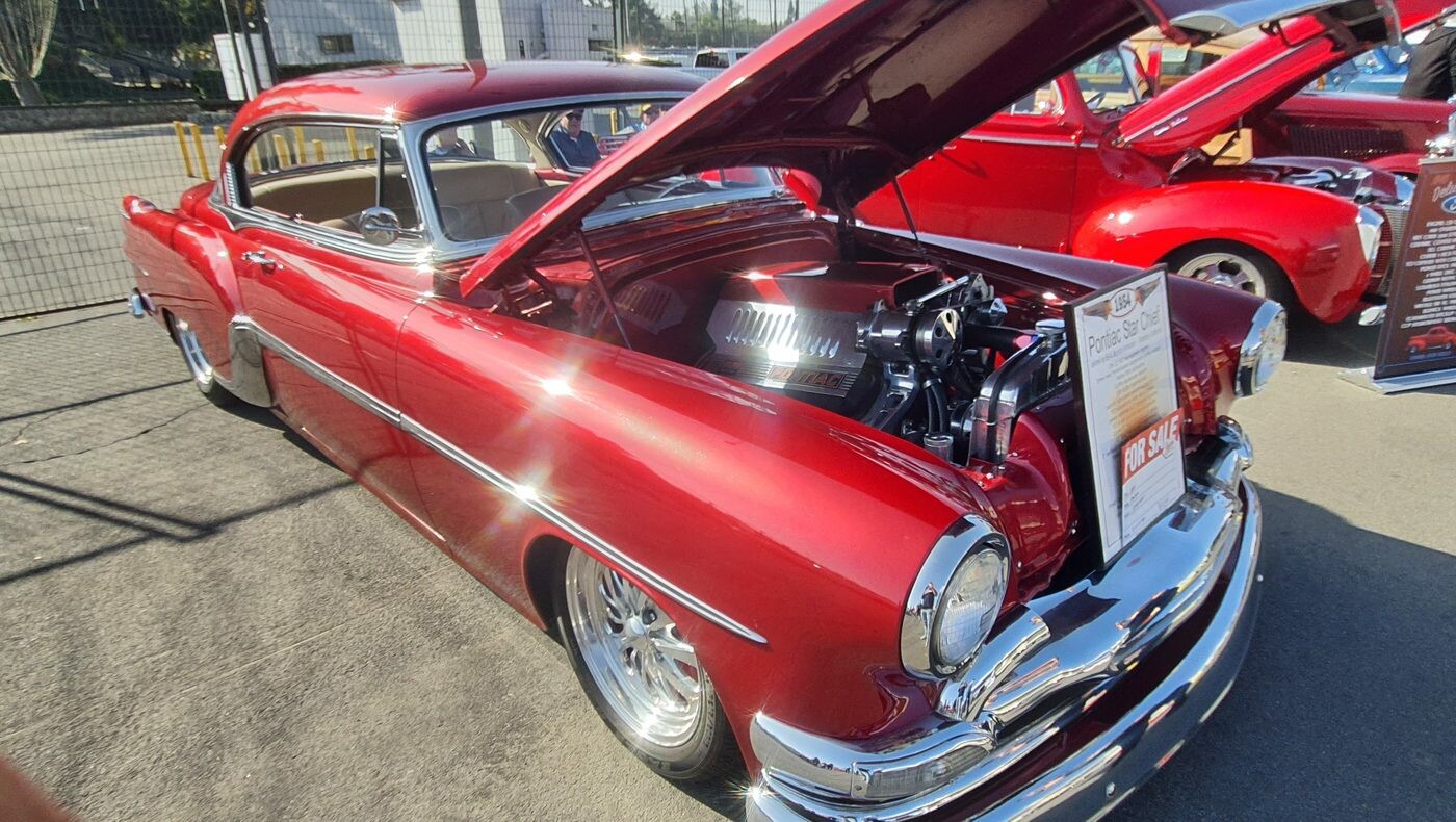 Czerwony Pontiac Chieftain z 1953 roku z silnikiem Pontiaca pod maską – kustom ze srebrnymi smugami