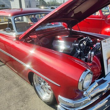 Czerwony Pontiac Chieftain z 1953 roku z silnikiem Pontiaca pod maską – kustom ze srebrnymi smugami