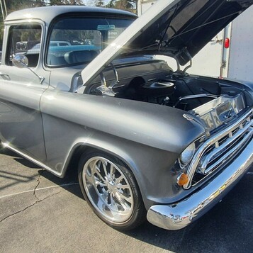 Srebrny Chevrolet 3100 Task Force z 1957 roku z otwartą maską – pickup z panoramiczną szybą