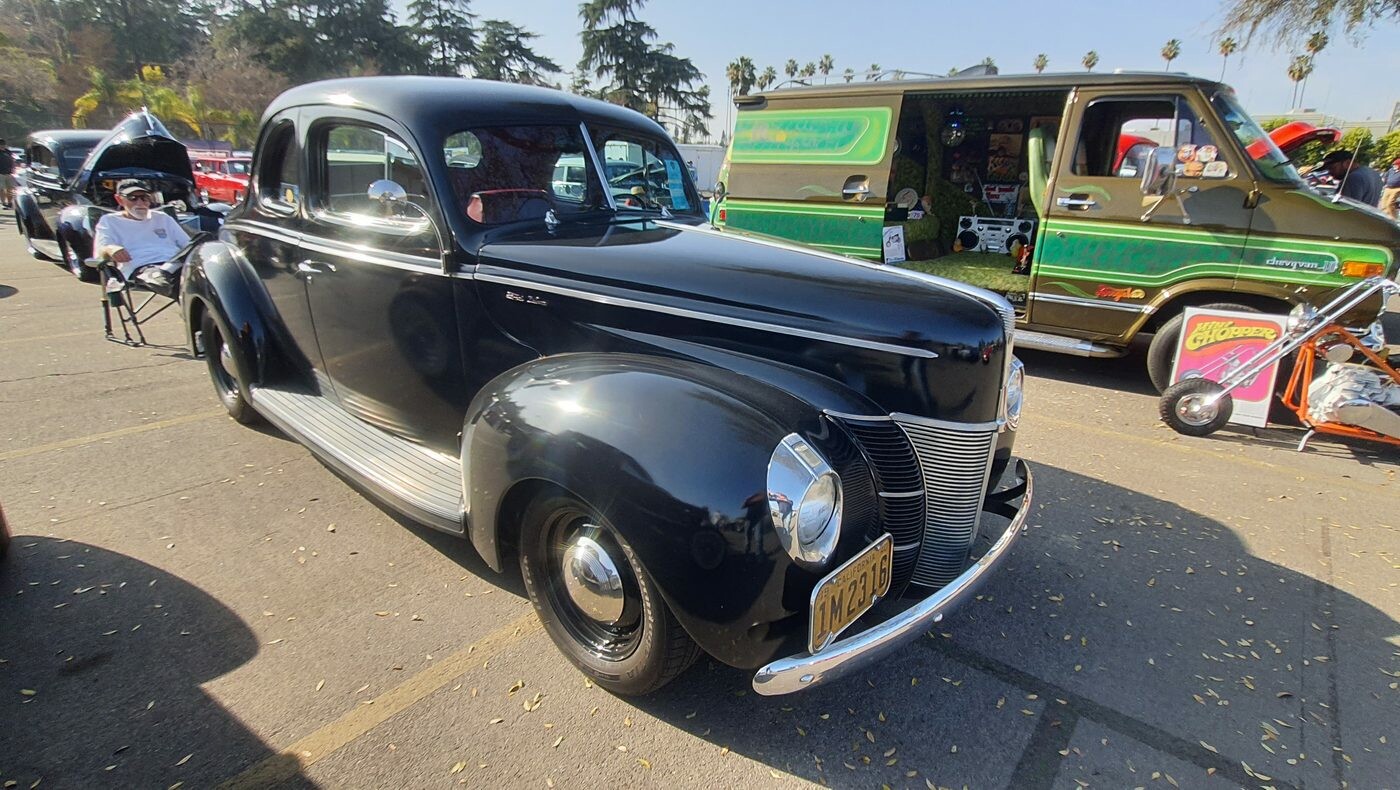 Czarny Ford Deluxe coupe z 1940 roku w oryginalnym stylu – przedwojenna elegancja obok kolorowego vana
