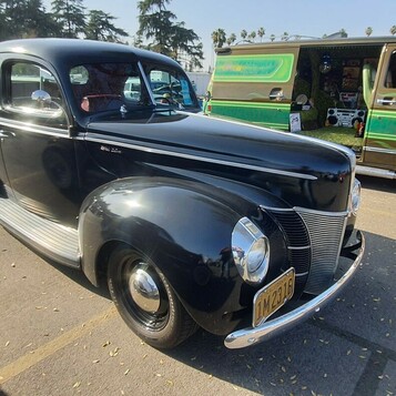 Czarny Ford Deluxe coupe z 1940 roku w oryginalnym stylu – przedwojenna elegancja obok kolorowego vana