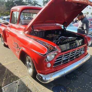 Czerwony Chevrolet 3100 Task Force z 1956 roku z czarnymi płomieniami – pickup z otwartą maską