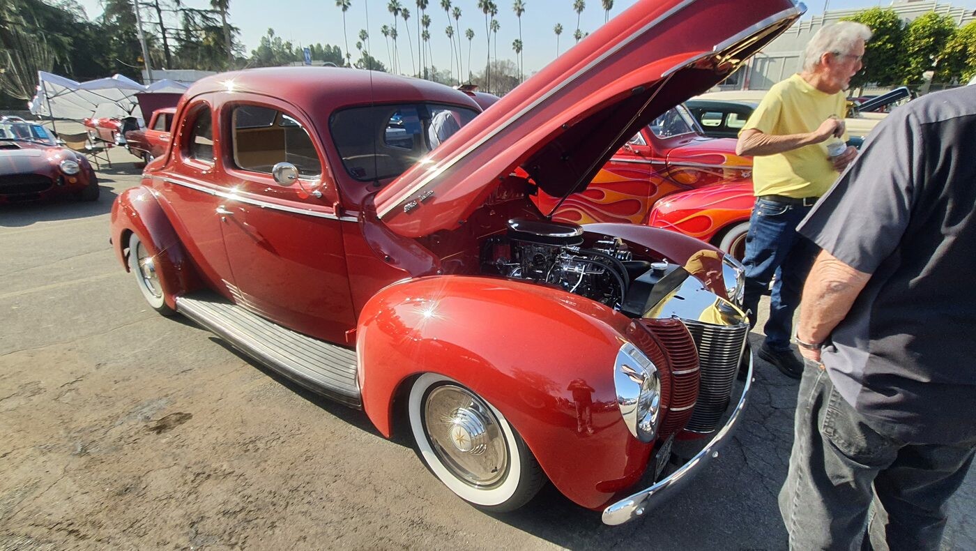Czerwony Ford Deluxe Tudor sedan z 1940 roku z otwartą maską – dwudrzwiowy sedan na białych ściankach