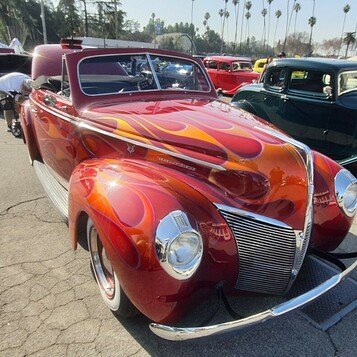Czerwony Ford Deluxe coupe z 1940 roku w pomarańczowo-żółtych płomieniach – kustom w ogniu