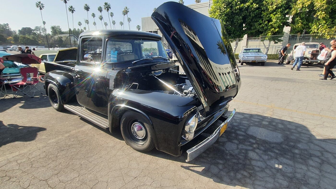 Czarny Ford F-100 z 1955 roku z otwartą maską – klasyczny pickup na chromowanych kołpakach