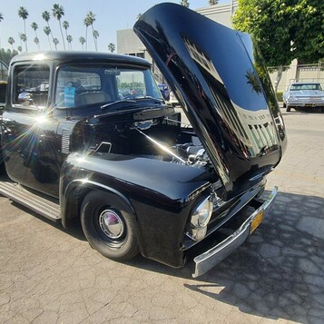 Czarny Ford F-100 z 1955 roku z otwartą maską – klasyczny pickup na chromowanych kołpakach