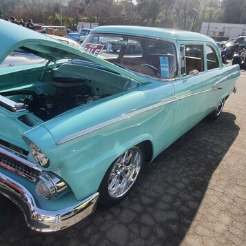 Turkusowy Ford Fairlane z 1955 roku z otwartą maską – dwudrzwiowy sedan z chromowaną kratką na polerowanych felgach