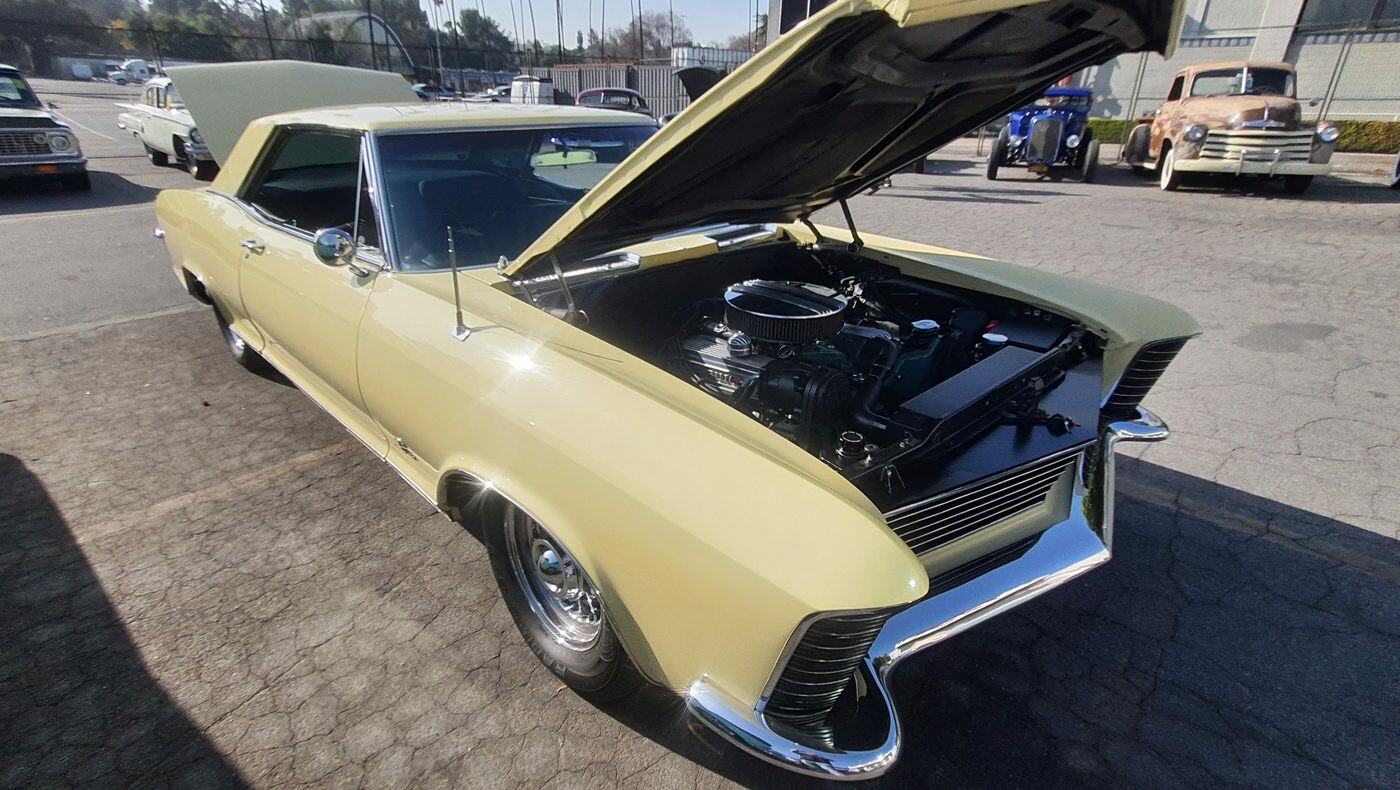 Kremowy Buick Riviera z 1965 roku z otwartą maską – chowane reflektory i silnik Nailhead