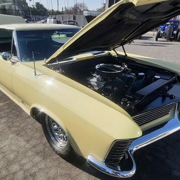 Kremowy Buick Riviera z 1965 roku z otwartą maską – chowane reflektory i silnik Nailhead