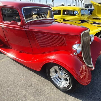 Czerwony Ford Tudor sedan z 1934 roku – przedwojenny street rod z pochyloną atrapą na polerowanych felgach
