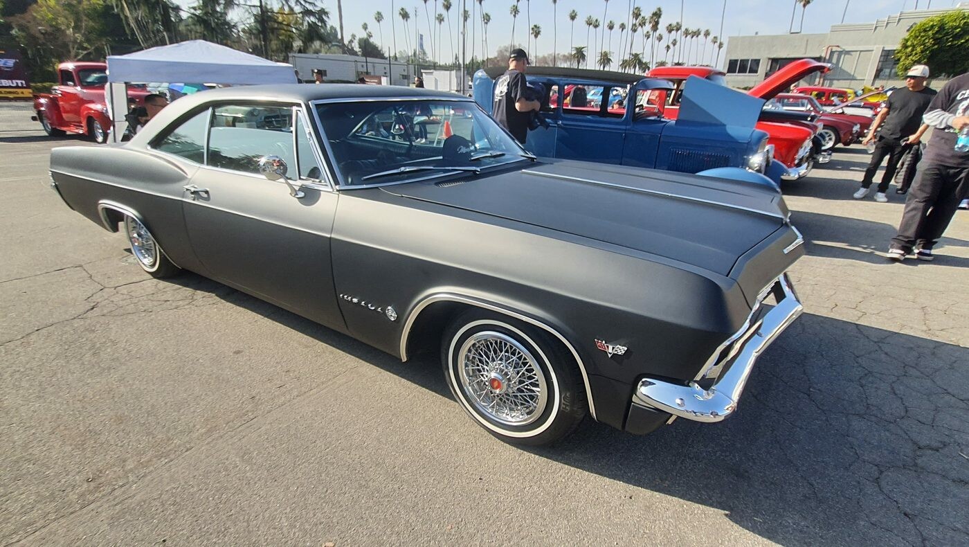 Satynowo-czarny Chevrolet Impala z 1965 roku z otwartą maską – lowrider na drucianych felgach
