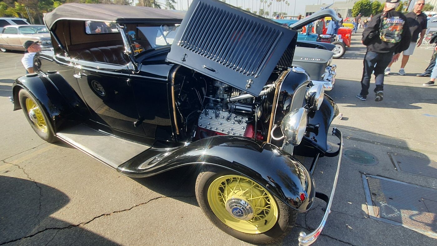 Czarny Ford roadster z 1932 roku w pełnych błotnikach na żółtych drucianych kołach – Deuce z otwartą maską