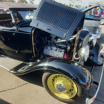 Czarny Ford roadster z 1932 roku w pełnych błotnikach na żółtych drucianych kołach – Deuce z otwartą maską
