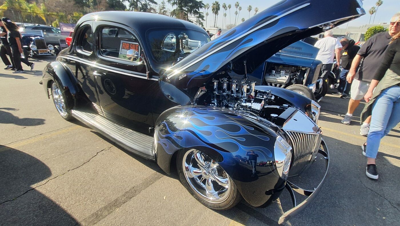 Granatowy Ford Deluxe coupe z 1940 roku z ghost flames i wtryskiem Hilborn – osiem trąb pod otwartą maską