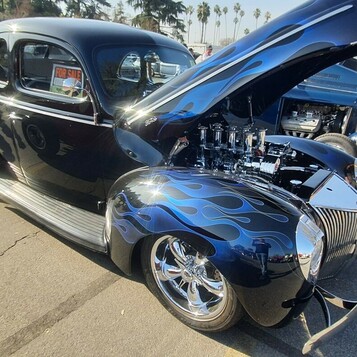 Granatowy Ford Deluxe coupe z 1940 roku z ghost flames i wtryskiem Hilborn – osiem trąb pod otwartą maską