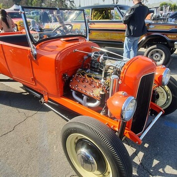 Pomarańczowy Ford Model T roadster pickup z 1927 roku – hot rod z silnikiem na wierzchu na kremowych felgach