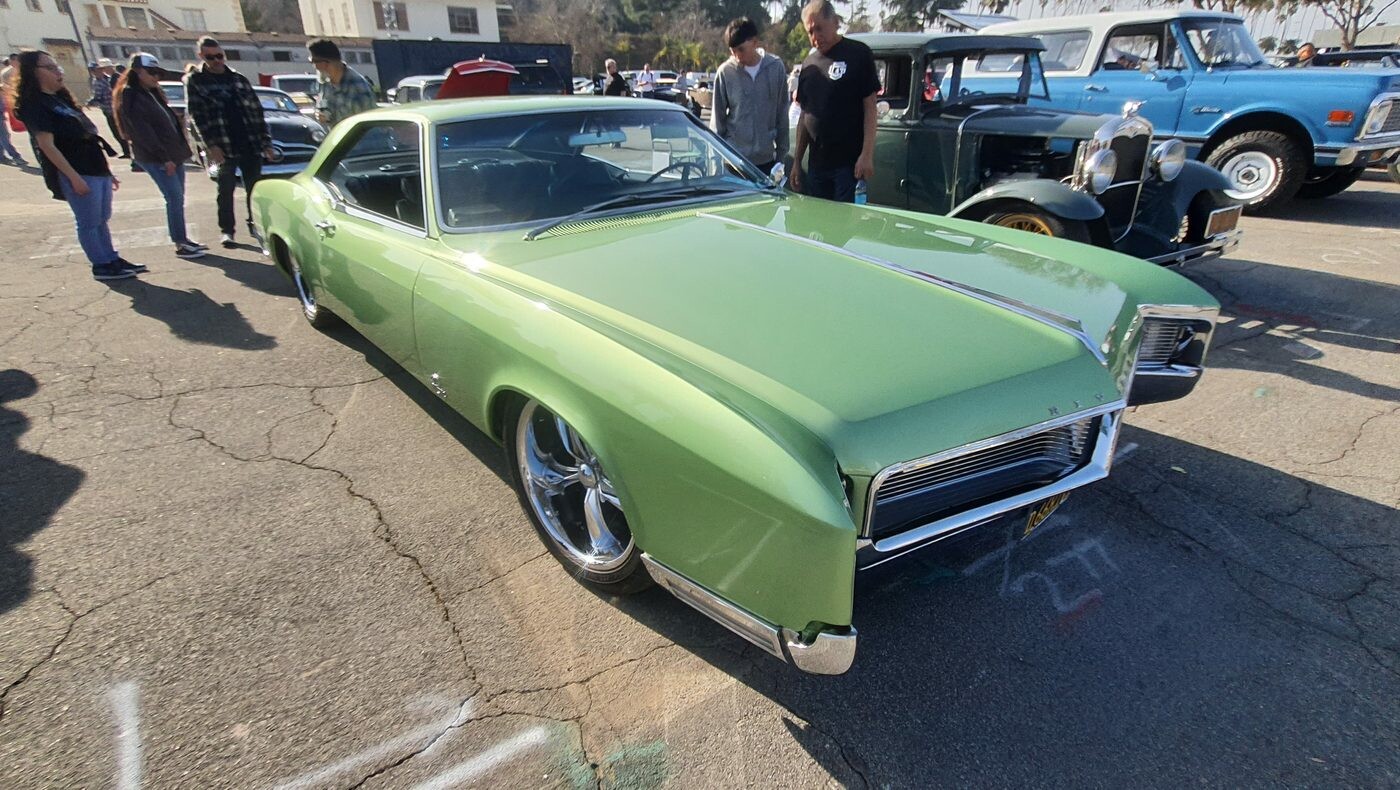 Jasnozielony Buick Riviera z 1967 roku – długi coupe z chowanymi reflektorami na polerowanych felgach