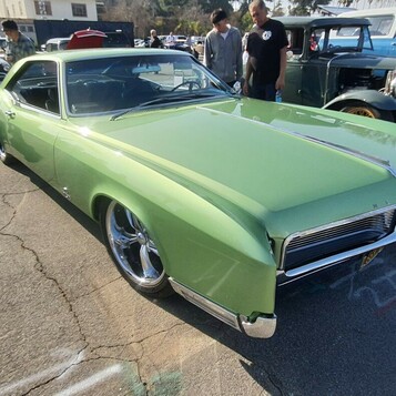 Jasnozielony Buick Riviera z 1967 roku – długi coupe z chowanymi reflektorami na polerowanych felgach