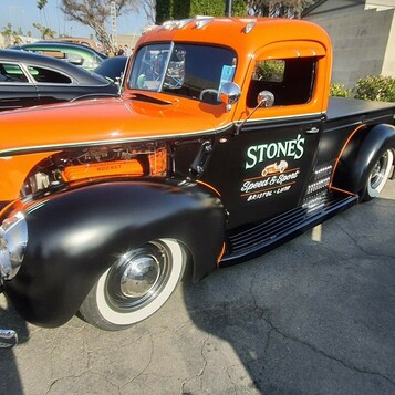 Pomarańczowo-czarny Ford pickup z 1941 roku z napisem warsztatu – firmowa ciężarówka jako kustom