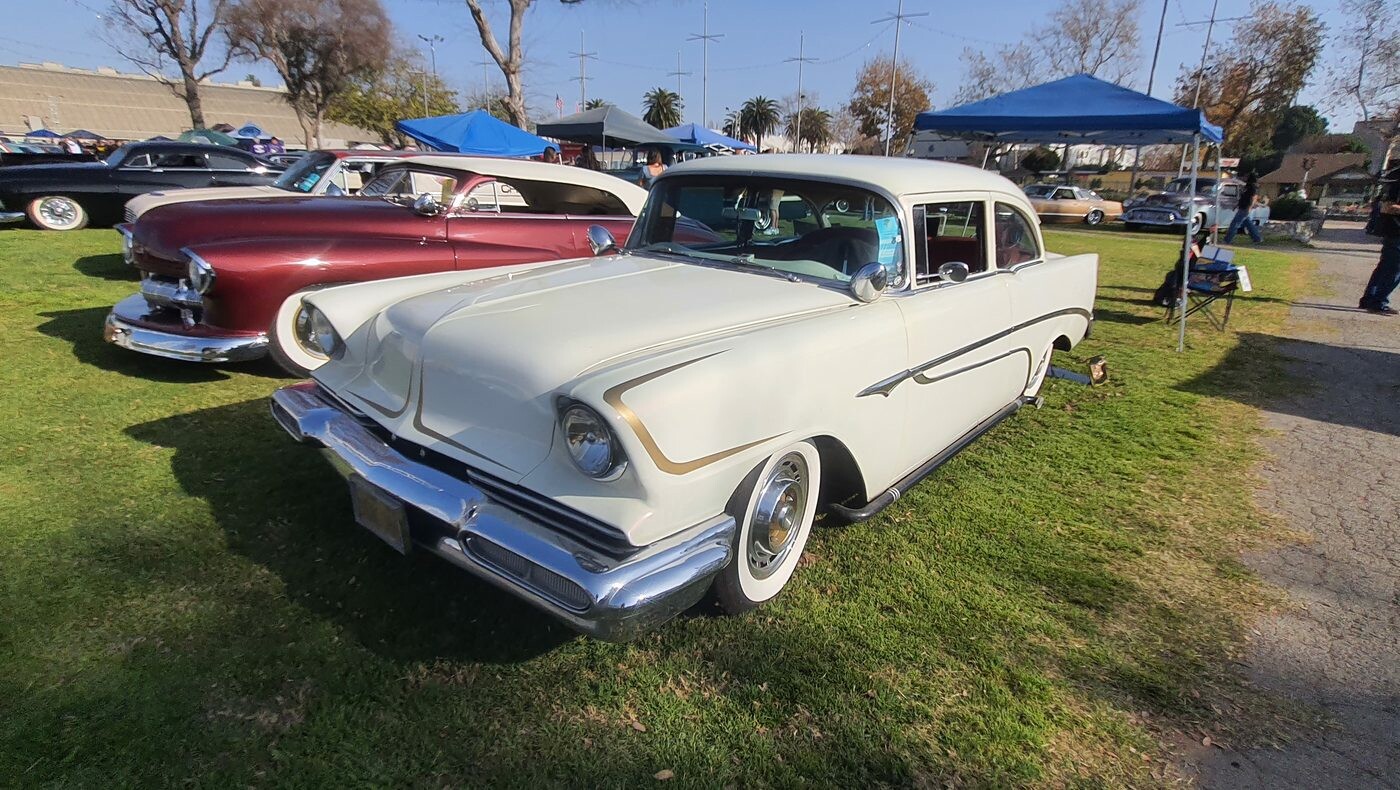 Biały Chevrolet 210 z 1956 roku jako mild kustom – wtopione reflektory, rurowa atrapa i złote scallopsy