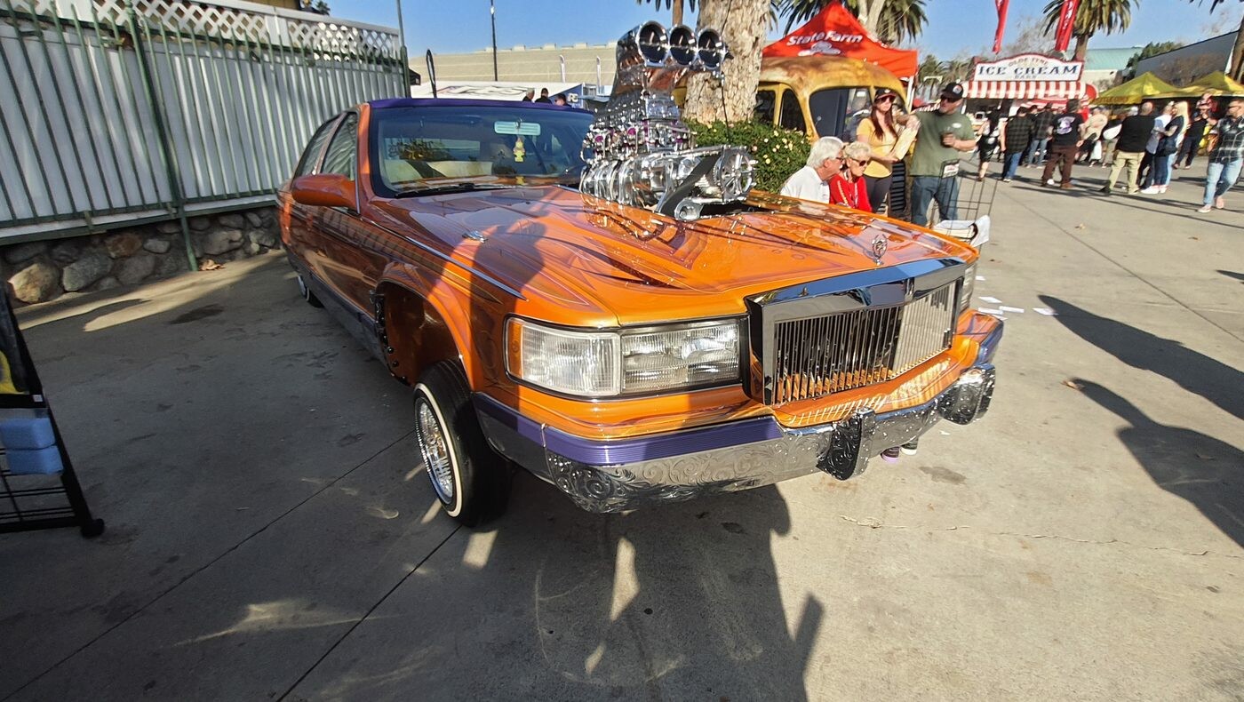 Pomarańczowo-fioletowy Cadillac Fleetwood Brougham lowrider z kompresorem przez maskę – złoto, chrom i hydraulika