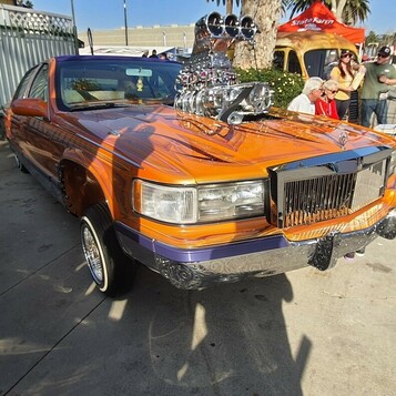 Pomarańczowo-fioletowy Cadillac Fleetwood Brougham lowrider z kompresorem przez maskę – złoto, chrom i hydraulika