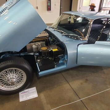 Błękitny Jaguar E-Type Series 1 coupe z otwartą maską – brytyjska legenda na drucianych kołach w hali zlotu