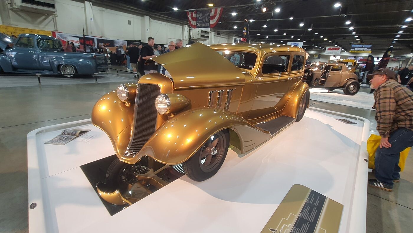 Złoty Ford Tudor sedan z 1934 roku na hali wystawowej – chopped street rod na lustrzanej podłodze