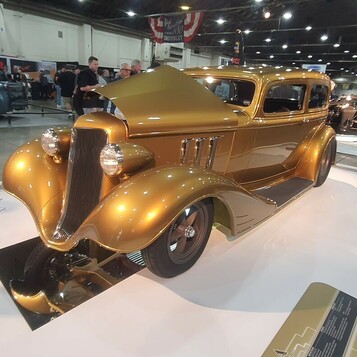 Złoty Ford Tudor sedan z 1934 roku na hali wystawowej – chopped street rod na lustrzanej podłodze