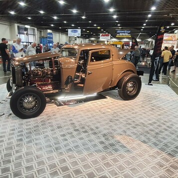 Miedziany Ford 3-window coupe z 1932 roku w hali – highboy na wzorzystej podłodze wystawowej