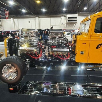 Żółta ciężarówka z dwoma silnikami i kompresorami – „Burnout Machine” na lustrach w hali wystawowej