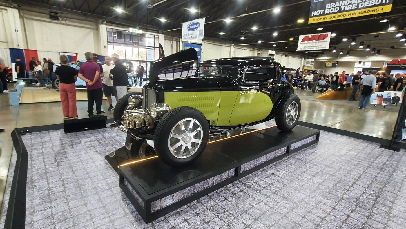 Czarno-limonkowy Ford 5-window coupe z 1932 roku na podeście – Deuce highboy w hali wystawowej