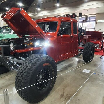 Czerwony Dodge Power Wagon crew cab z lat 70. na wielkich oponach – terenowy pickup z otwartą maską w hali