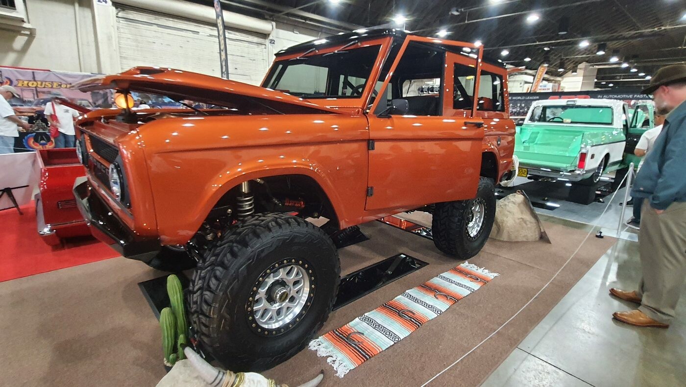 Pomarańczowy Ford Bronco pierwszej generacji na wielkich oponach – terenowa legenda w hali zlotu