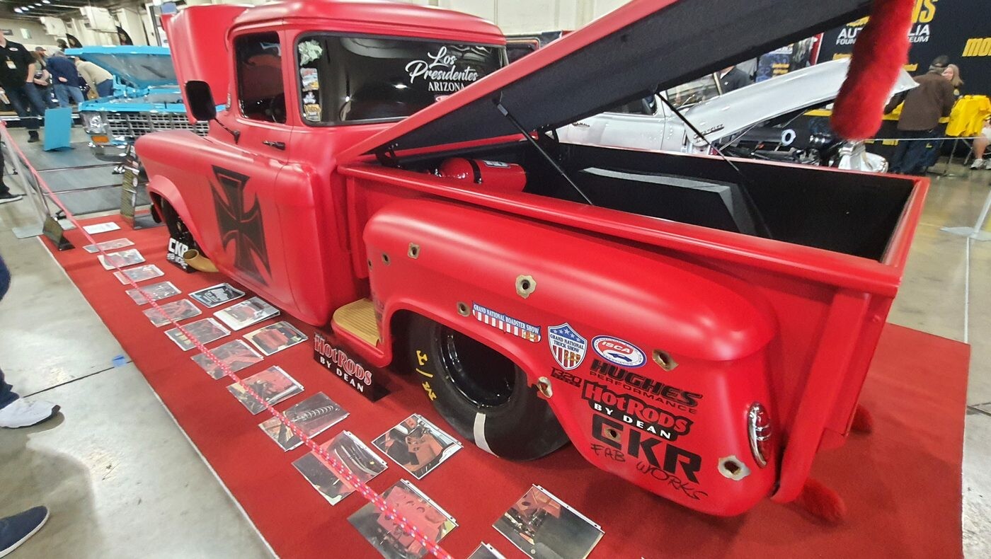 Matowo-czerwony Chevrolet Task Force z naklejkami sponsorów – shop truck z otwartą maską w hali