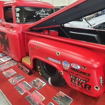 Matowo-czerwony Chevrolet Task Force z naklejkami sponsorów – shop truck z otwartą maską w hali