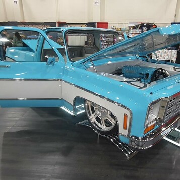 Błękitno-biały Chevrolet C10 square body z kompresorem – otwarta maska i drzwi na wystawie